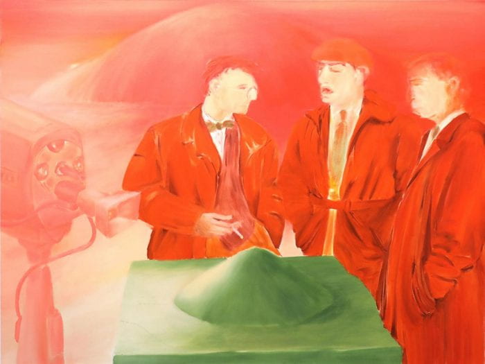 Three men in red suits on red background standing around a green table with green mound on it.