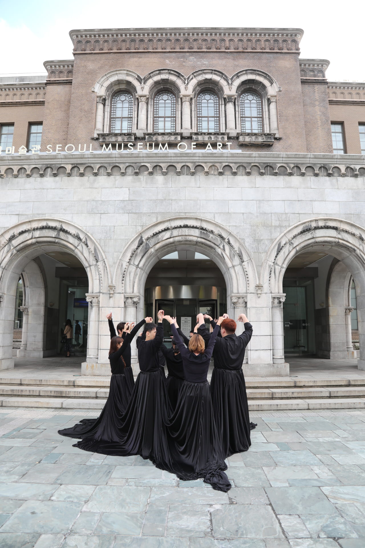 Performers in black collected in a group. In-Out performance, Seoul Museum of Art, Korea