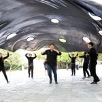 Performers in black under large perforated sheet. In-Out performance, Seoul Museum of Art, Korea
