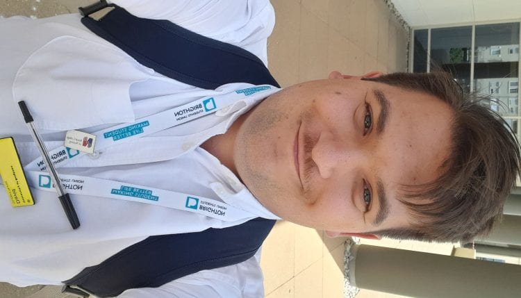 David Vago smiling in selfie wearing rucksack and nursing badge