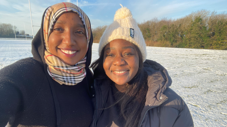 A photo of Darine (left) and Mitchelle (right) smiling in the snow in Brighton