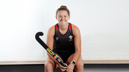 Lauren Roberts smiling holding a hockey stick