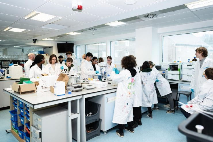 School students wearing lab coats learning in a science lab