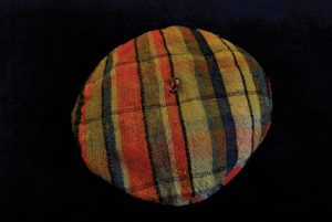A cloth tam-o'shanter cap with red, blue and beige stripes.