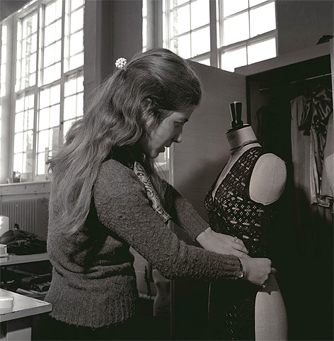 Greyscale photograph of young woman working with a fashion tailors dummy.