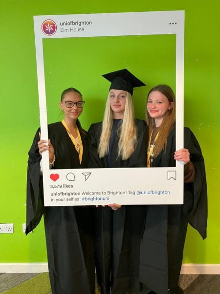 Three summer school students smiling in their graduation gowns