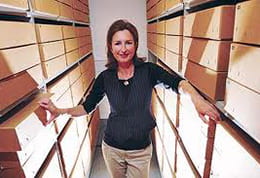 A colour photographs showing Dr Catherine Moriarty, Curatorial Director at the University of Brighton Design Archives, amongst archival boxes.