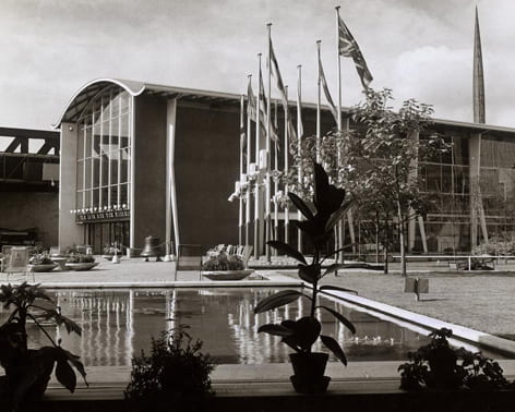 Black and white general view image from the Festival of Britain (1951), showing a pond and one of the Pavilions. From the Design Council Archive housed in the University of Brighton Design Archives.