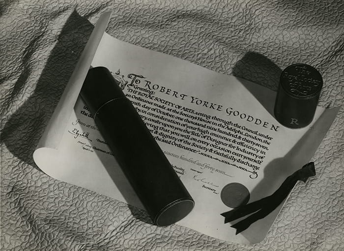 Black and white photograph of the Diploma of The Faculty of Royal Designers for Industry awarded to Robert Yorke Goodden.The leather scroll case is placed on top.