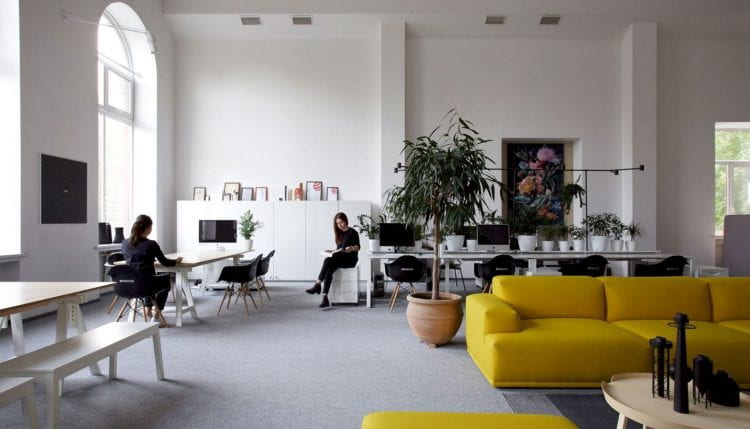 Image of a modern studio style office with two colleagues chatting.