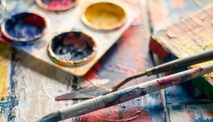 Paintbrushes covered in paint on a wooden table