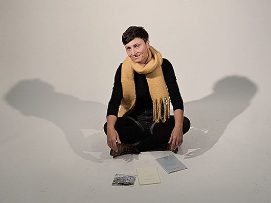 Portrait of Dr Patricia Kolaiti seated on floor with poetry books