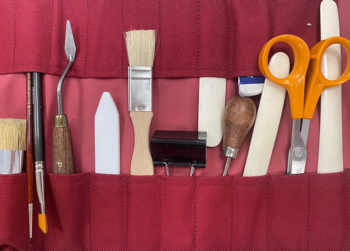 A red, rollable pouch filled with conservation tools