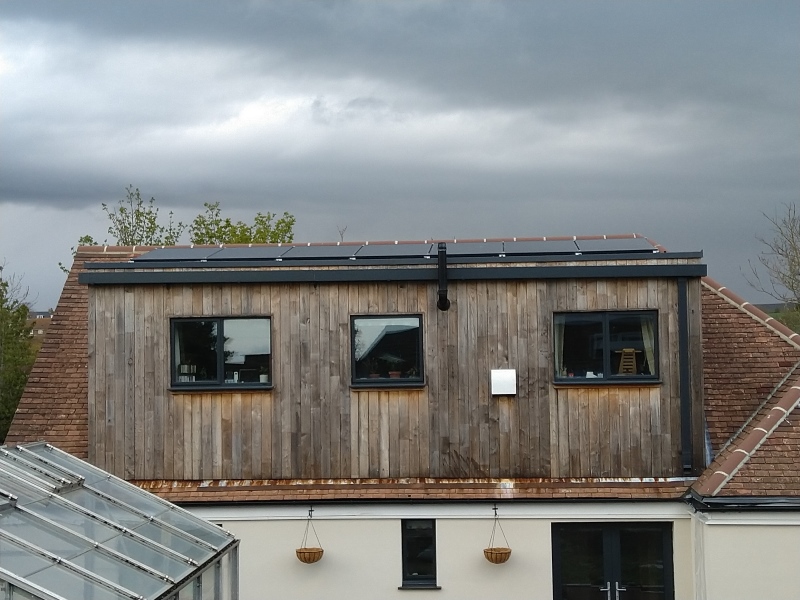 timber clad house with solar panels just showing on the roof.