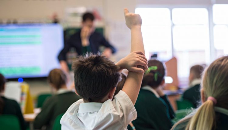 boy with hand up in primary classroom