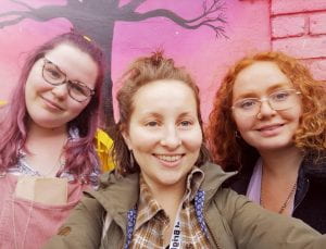 Selfie. Three young white women against pink background.