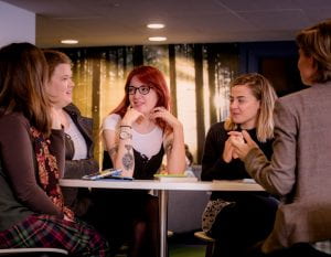 Portrait of five women talking around a table