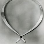 A silver necklace with a bow-tie like fastening at front
