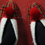 Pair of red tartan slippers with white edges and red pompom
