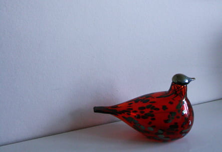 A cropped version of a portrait of Hanna Drummond taken by Sirpa Kutilainen, showing a decorative Ruby Bird designed by Oiva Toikka.
