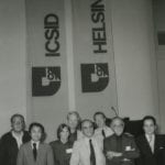 Group of eight people standing in front of some banners