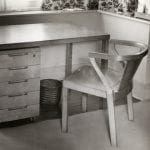 A wooden writing desk with five drawers and matching wooden chair