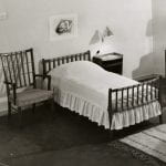 Black and white photo of bedroom furniture setting showing bed, chairs and dressing table