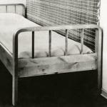 Black and white photo of a single bed made of birch with curved ends