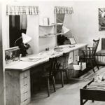 A black and white photo of a childrens room setting with bunk beds and desks