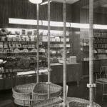 A black and white photo of a grocery shop setting with goods displays on the walls