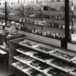 A black and white photo of a perfume shop setting with bottles on shelves