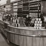 A black and white photo of a grocery department store setting with curved counter