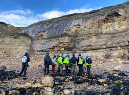 Group of students working by cliffs on the beach