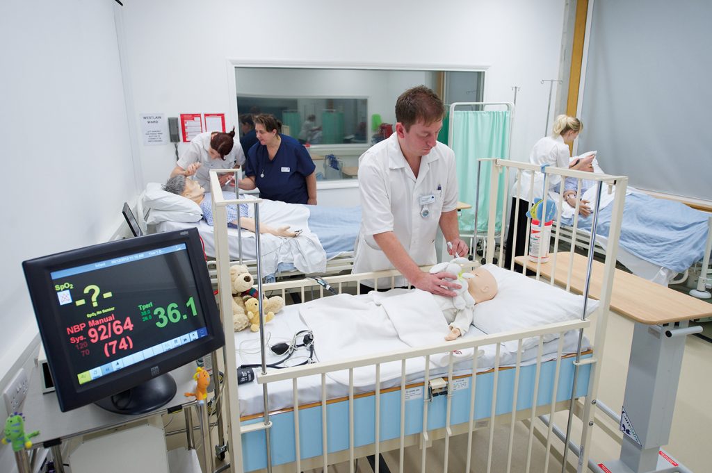Nursing students working in a training ward with beds and clinical machines