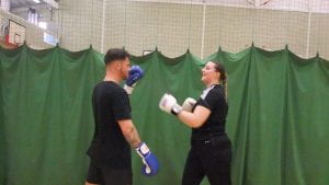 male and female student laughing as they box