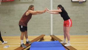 two students on beams balancing against each other