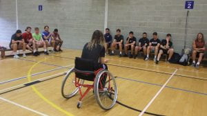 female in wheelchair talking to students