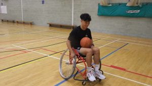 male student in wheelchair with a basketball ball on lap