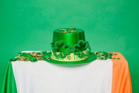 Irish flag with green hat on it and plastic four leaf clover.