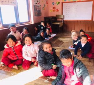 a smiling group of children in their classroom