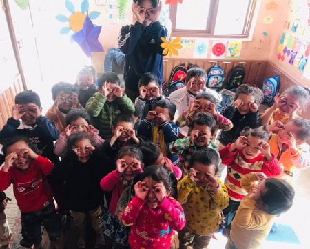 children holding their fingers to their eyes like glasses