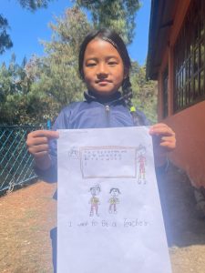 A child holding a drawing showing that she would like to be a teacher