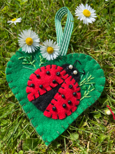 felt heart on the grass with some daisies