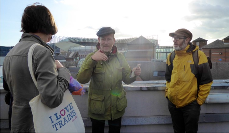 Dr Mikey Tomkins talking to two other people in an outdoor urban setting. (Source: Dr Mikey Tomkins)