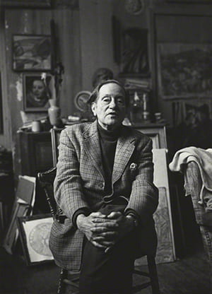 Black and white portrait of Duncan Grant sitting on a chair looking at the camera