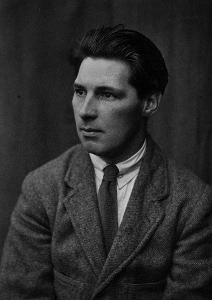 A black and white portrait of James Hogan looking into the distance, wearing a wool suit