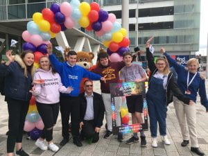 Young people supporting the resilience message, waving under a bunch of colourful balloons