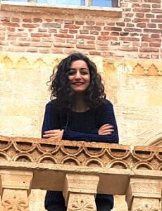 Photo of Buket Kara leaning on a stone balcony
