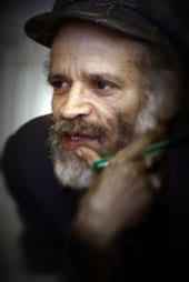 Photo of John Agard looking to the left, hand near face