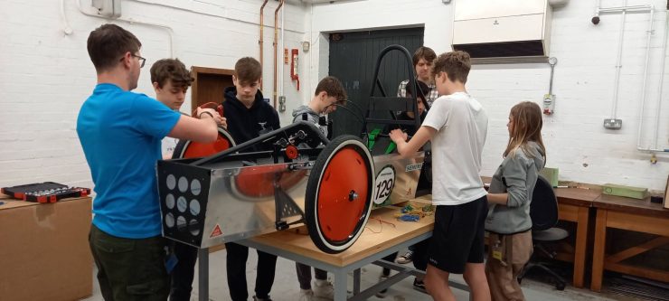 Group of students working on a car in the lab